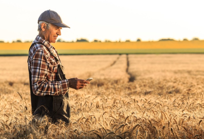 Man standing in a field holding a handheld weather station